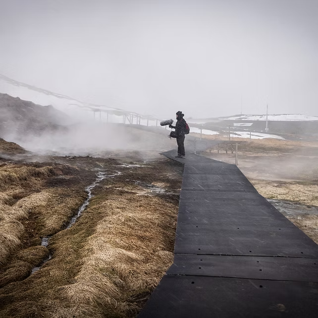Person explores misty landscape on a black path, capturing atmospheric sounds for Mayo Dark Sky Festival.