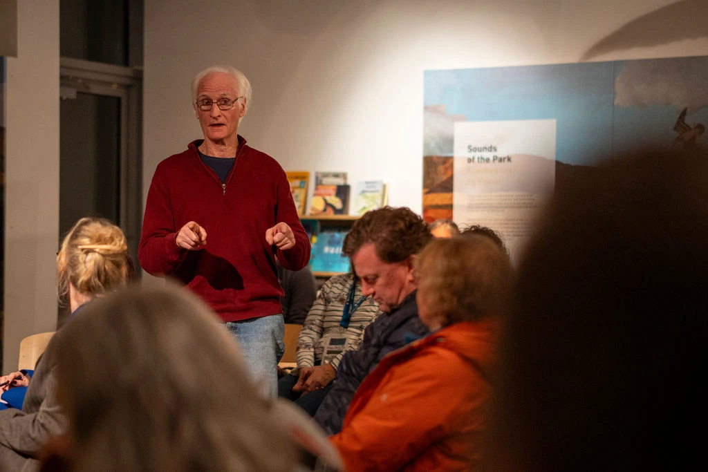 Speaker engaging audience at Mayo Dark Sky Festival event, discussing astronomy and park sounds in a cosy setting.