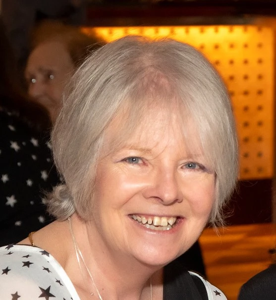 Female attendee at the Mayo Dark Sky Festival, smiling indoors, with warm lighting in the background.
