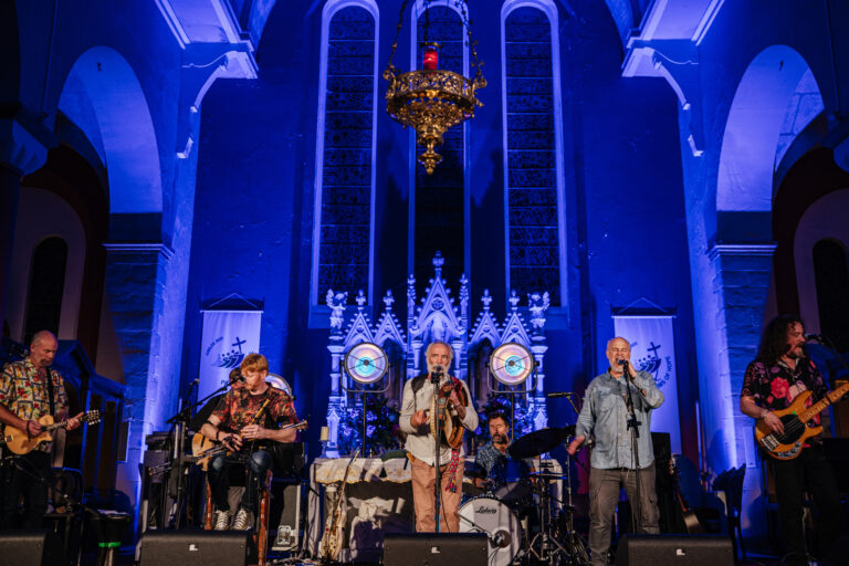 Band performing at Mayo Dark Sky Festival in ornate church setting under vibrant blue lighting.