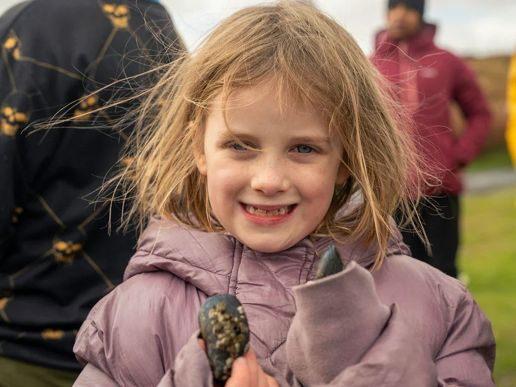 Child enjoying Mayo Dark Sky Festival events outdoors, holding stones.