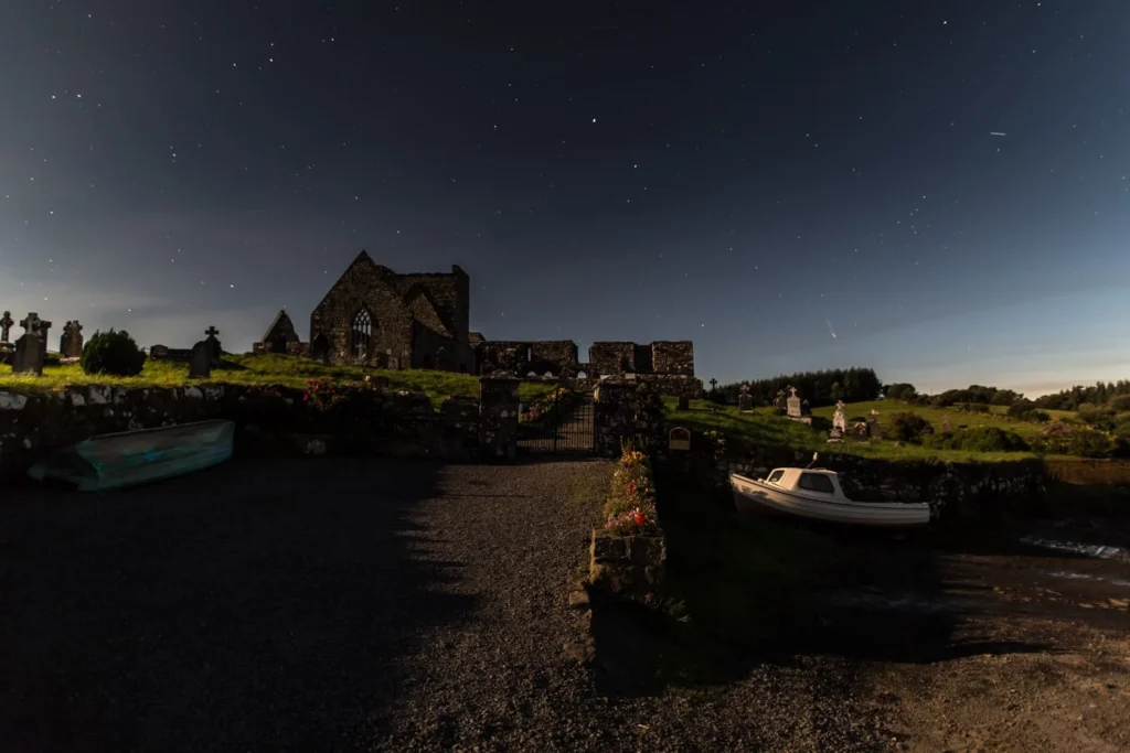 Ancient ruins under starry night sky at Mayo Dark Sky Festival, Ireland. Peaceful evening atmosphere by the water.